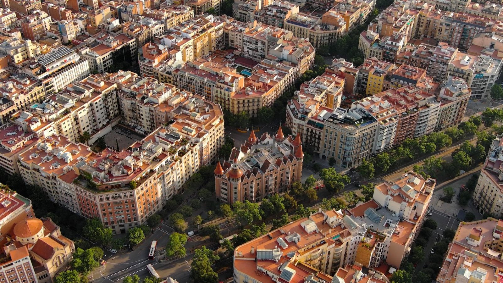 Aerial view of Eixample in Barcelona showing residential buildings, tree-lined streets, and modernist architecture