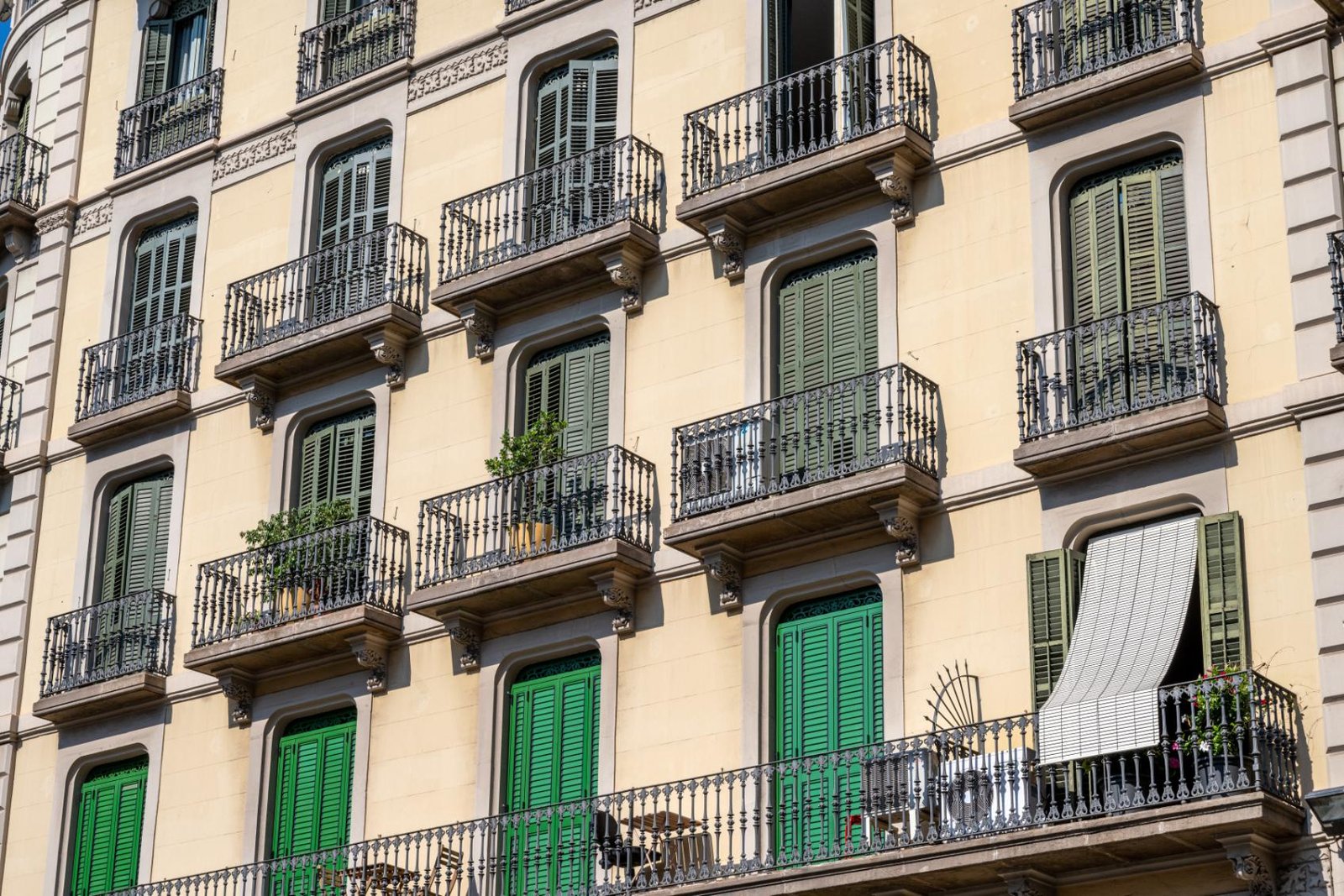 Traditional Barcelona apartment facade in Gràcia with balconies and green shutters